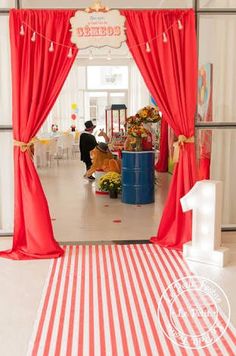 the entrance to a children's play area with red curtains and white flooring