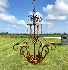 an iron chandelier in the middle of a grassy field with a barn in the background