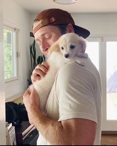 a man holding a small white dog in his arms