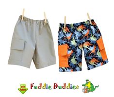 two children's shorts with dinosaurs on them, one is grey and the other is orange