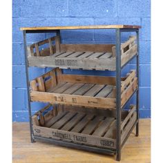 three wooden crates stacked on top of each other in front of a blue brick wall