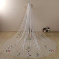 a wedding veil with flowers on the bottom and green trimmings around the edge