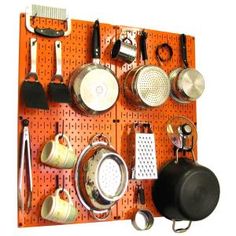 an orange peg board with pots and pans on it