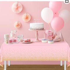 a pink table topped with a cake and lots of balloons