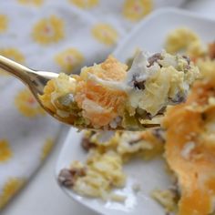 a close up of a spoonful of food on a white plate with yellow flowers