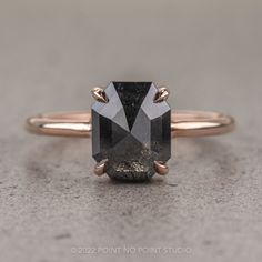 an image of a black diamond ring on the ground in front of a gray background