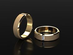 two gold wedding bands with a diamond in the middle on a black background, one is slightly