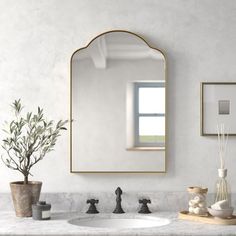 a bathroom with marble counter tops and white walls, along with a gold framed mirror