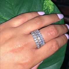 a woman's hand with two rings on it and a green plant in the background