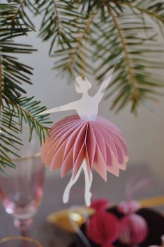 a paper ballerina ornament hanging from a christmas tree