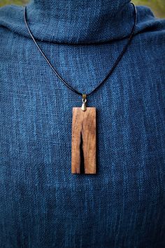 a person wearing a blue sweater with a wooden pendant on it's neck,