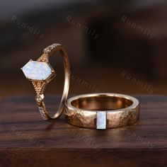 two gold rings with white opal and diamond accents on top of a wooden table