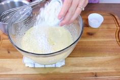 a person mixing batter in a bowl on top of a wooden cutting board