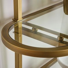 a round glass table with brass frame and wood trim around the edge, against a white wall