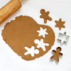 gingerbread cookies and cookie cutters on a white surface with a rolling pin next to them