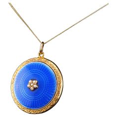 We are delighted to offer this splendid late Victorian/early Edwardian blue enamel pendant necklace made c.1900 in 9ct solid gold. Striking and distinguished from contemporary pieces, this pendant necklace features a wonderful blue enamel guilloche design in the centre with a fine engine-turned pattern underneath. The blue enamel has a gorgeous hue which is elegant in the shadows, yet presents more vibrancy when exposed to sunlight with its glossy surface. In addition to its rich enamelling, the centre is embellished with a cluster of seed pearls as if to form a flower. A wonderful accent and touch to the overall piece making it a lovely and distinguished piece of antique jewellery. The reverse side presents a locket with a glass panel in which a photo of a loved one may be placed within. Yellow Gold Enamel Medallion Necklace, Luxury Blue Locket Jewelry, Luxury Blue Locket Necklace, Victorian Enamel Locket Jewelry, Blue Enamel Locket Jewelry, Antique Blue Necklaces For Formal Occasions, Heirloom Blue Necklaces For Weddings, Luxury Blue Medallion Jewelry, Victorian Enamel Yellow Gold Necklace