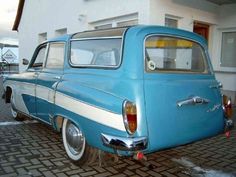 an old blue and white car parked in front of a building