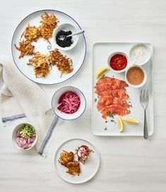 two plates with different types of food on them next to bowls and utensils