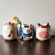 three ceramic pig vases sitting on top of a wooden table