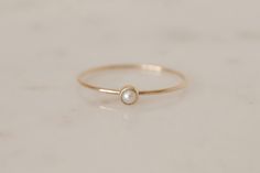 ELLA 14K Gold Pearl Ring - a gorgeous everyday piece. For a simple and feminine look, wear it just by itself or stack it up with our BELLA Simple Band or LIV Twisted Band Stacking Rings. Materials - 14k recycled solid gold, quality marked - approx. 0.8mm band width - smooth and shiny texture - 3mm Pearl size, round cut cabochon Freshwater Pearl, cultured - never wild caught. Only the prettiest pearls are handpicked for your jewelry. As natural products they may slightly differ in color and shape Elegant 14k Gold Filled Promise Ring, 14k Gold Solitaire Jewelry For Everyday, Elegant 14k Gold Filled Rings, Elegant 14k Gold-filled Rings, Simple Round 14k Gold Jewelry, Simple Gold Solitaire Jewelry, Simple 14k Gold Jewelry With Simple Design, Dainty Solitaire Jewelry In Recycled Gold, Simple 14k Gold Solitaire Jewelry