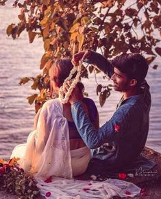 a man and woman sitting next to each other near the water