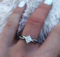 a woman's hand with a diamond ring on top of her finger and white nail polish