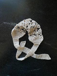 a white crocheted ribbon on a black surface