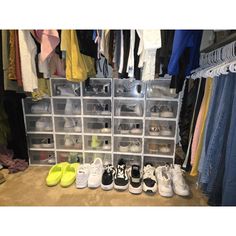 several pairs of shoes are lined up on the floor in front of a rack full of clothes