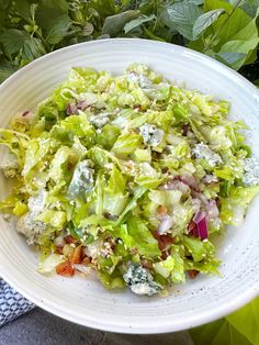 a white bowl filled with lettuce and other food items on top of a table