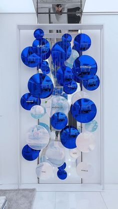 a display case with blue and white glass objects hanging from it's sides in a room