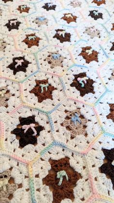 a crocheted blanket is laying on top of a tablecloth with teddy bears