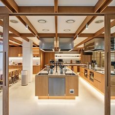 an open kitchen and dining room area with wooden beams on the ceiling, along with white flooring