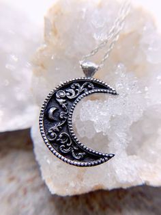 "A crescent shaped moon with a solid bail. Inside the moon is a floral scrollwork pattern. We cast this is solid sterling silver, with a dark patina to really make it pop! Pendant including bail is 26mm high and 20mm wide. This item is custom made to order. That means it may take an extra second or two to make your entire piece by hand. We try to beat shipping estimates, but its just a one woman team in this shop! Our supplier of casting grain uses SCS-certified 100% recycled metal. We make ever Silver Half Moon Jewelry Engraved, Silver Half Moon Engraved Jewelry, Crescent Silver Jewelry With Sun And Moon Design, Vintage Sterling Silver Moon Phase Jewelry, Vintage Moon Shaped Sterling Silver Jewelry, Vintage Sterling Silver Moon Jewelry, Vintage Moon-shaped Sterling Silver Jewelry, Vintage Sterling Silver Moon Phase Necklace, Vintage Silver Jewelry With Moon Phase