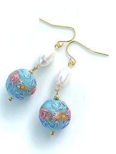 These beautiful handmade Murano glass earrings feature light blue vintage venetian wedding cake beads with genuine white freshwater pearls. Each vintage lampwork bead features pretty pink rose swirls, yellow dots, and dark blue and white swirls. A faint foil gold stripe, known as aventurine, is also incorporated in each bead. Please note Venetian lampwork beads are handcrafted with a elevated texture and no two beads are exactly the same however I do pair beads that are similar in size. Gold sur Elegant Light Blue Jewelry With Large Beads, Czech Glass Round Jewelry For Wedding, Light Blue Round Beads Jewelry For Wedding, Whimsical Round Blue Jewelry, Whimsical Blue Round Jewelry, Unique Glass Jewelry For Wedding, Wedding Glass Bead Jewelry, Wedding Jewelry With Round Glass Beads, Light Blue Pearl Jewelry For Gift