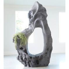 an artistic sculpture with moss growing on it's side and in front of a window