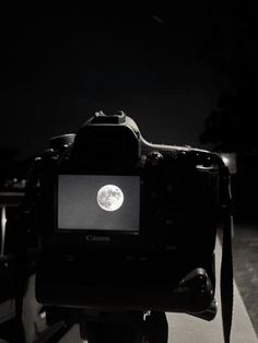 a camera is sitting on top of a table with the moon in the sky behind it