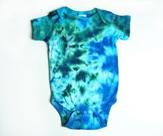 This short sleeve tie-dye baby bodysuit is dyed in beautiful ocean colors of turquoise, aqua, blues, and greens in a spattered pattern. The photos show the front and back views. Available in sizes: Newborn, 6 months, 12 months, 18 months, and 24 months. SizeBody WidthBody Length Newborn7 in13 in. 6 months;;8 1/2 in14 1/2 in. 12 months10 in16 in. 18 months11 in16 in. 24 months11 in18 1/2 in. The bodysuit is a Rabbit Skins brand, short sleeve, 100% cotton, nice quality. Lap shoulder sleeves, three Casual Green Onesie For Summer, Green Short Sleeve Cotton Onesie, Green Cotton Short Sleeve Onesie, Green Cotton Shortsleeved Onesie, Green Cotton Short-sleeve Onesie, Green Fitted Casual Onesie, Multicolor Short Sleeve Onesie For Summer, Casual Blue Onesie For Summer, Casual Blue Summer Onesie