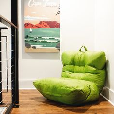 a green bean bag chair sitting on top of a hard wood floor next to a white wall