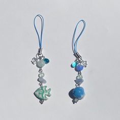 two blue and white earrings with charms hanging from them