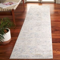 a white runner rug on a wooden floor in front of a door with a plant