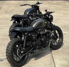 a black motorcycle parked on top of a cement floor next to a parking lot with no one around it