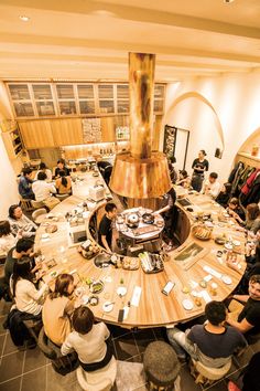 a group of people sitting around a table with food on it and a stove in the middle