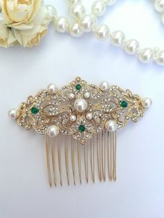 a close up of a hair comb with pearls and emeralds on it next to a flower