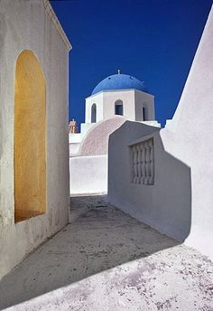 an alley way with white buildings and blue domes