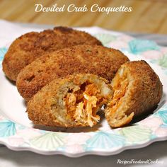 fried crab croquettes cut in half on a floral plate with the words deviled crab croquettes