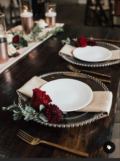 two white plates with red flowers on them sitting on a table next to each other