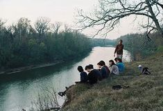 group of people sitting on the bank of a river