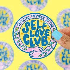 someone holding up a sticker with the words self love club in front of them