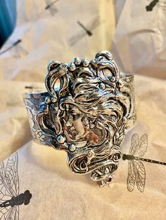 Art Nouveau style cuff.  Magnificent hand crafted Alphonza Mucha style Lady Cuff. From MyElegantThings Design Studio"  Antique silver plated over brass cuff. Engraved cuff with gorgeous flowers and vines and leaves. Vintage style very limited edition Cuff is an engraved and gorgeous garden piece. 1 inch width. Woman piece is 1-1/2 inches. Gorgeous and what a statement. Collectible Silver Cuff Bracelets, Collectible Silver Cuff Bracelet, Silver Collectible Cuff Bracelet, Silver Collectible Bracelets, Nickel Free Silver Cuff Bracelet, Silver Wearable Art Cuff Bracelet, Silver Cuff Bracelet Gift, Vintage Antique Silver Cuff Bracelet, Ornate Silver Cuff Bracelet