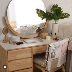 a mirror sitting on top of a wooden dresser next to a plant in a vase